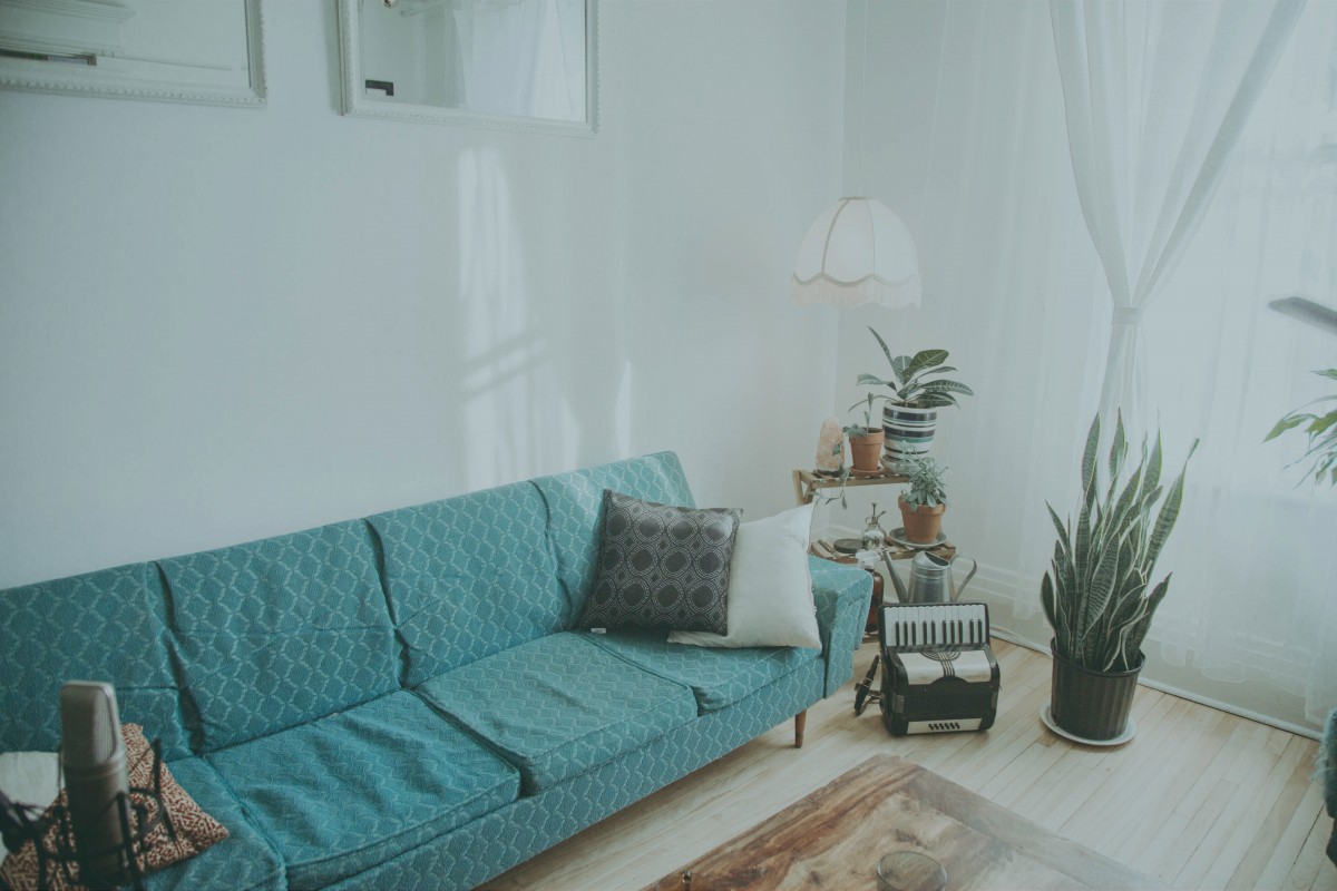 A blue couch in an apartment with white walls and minimalistic decorations