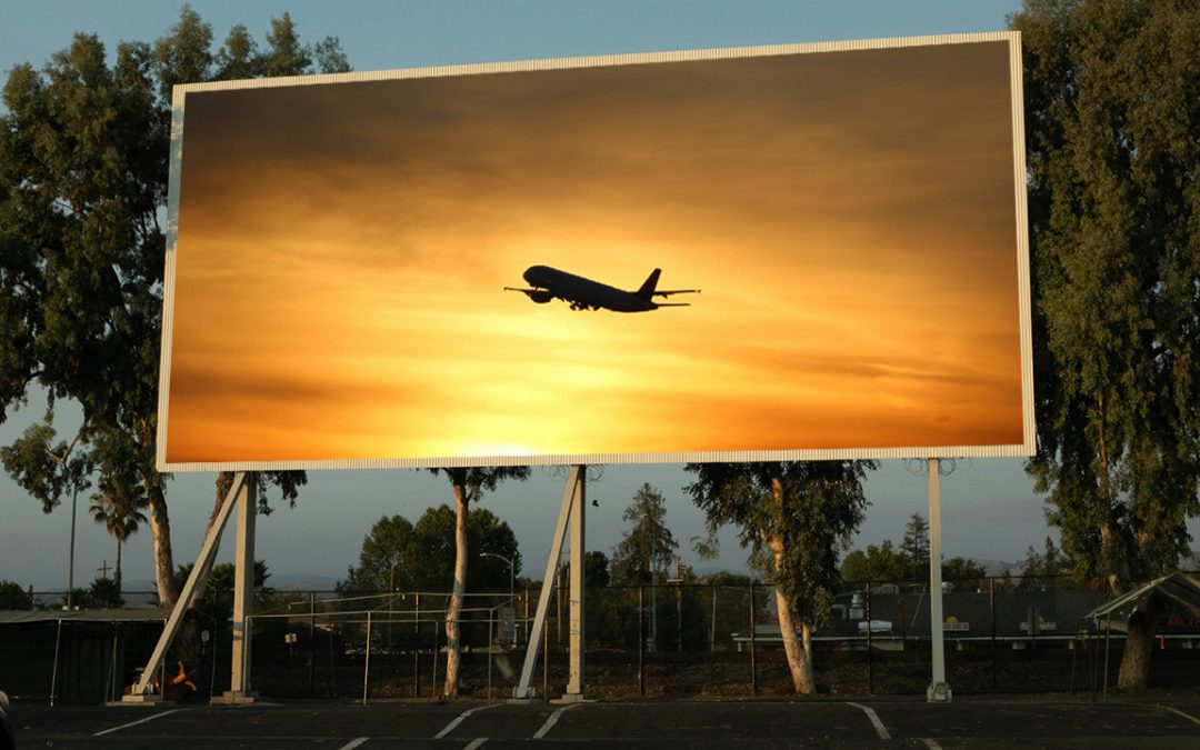 Flygplan i solnedgång på stor reklamskylt